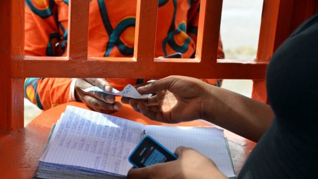 A woman withdraws money at an Orange Money cashier booth on May 20, 2015, in Abidjan. This mobile phone-based payment system allows customers to use their phones to pay their bills or to transfer funds to any other phone subscriber. AFP PHOTO / ISSOUF SANOGO (Photo by ISSOUF SANOGO / AFP)